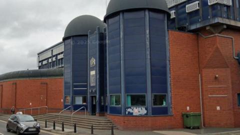 A large red brick building with a large blue entrance way with blue domes over it