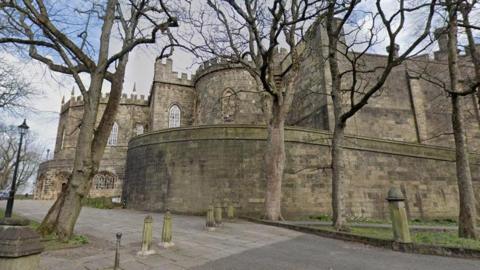 A stone building with arched mullioned windows, which is part of Lancaster Castle