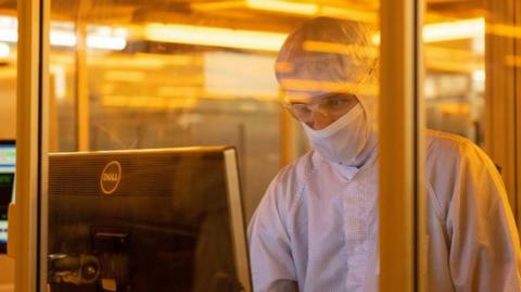 A worker in protective clothing, wearing a mask and glasses in a clean room for silicon semiconductor wafer manufacture at Nexperoa's former Newport plant in 2022.