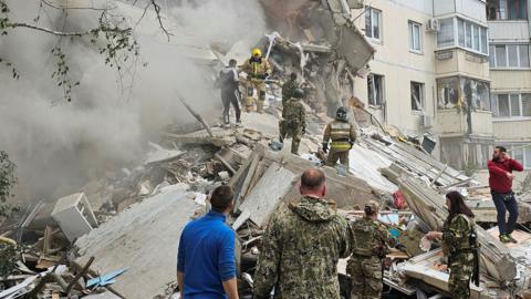 Emergency personnel climb on rubble after apartment collapse