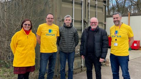 Five people stood in front of a shipping container