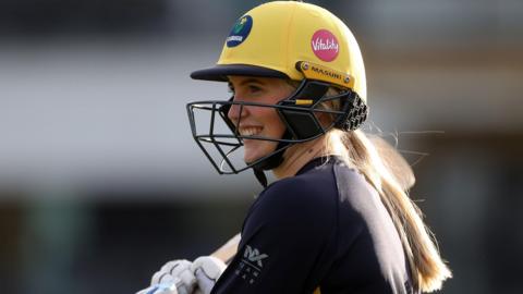 Charlotte Scarborough smiling through her batting helmet