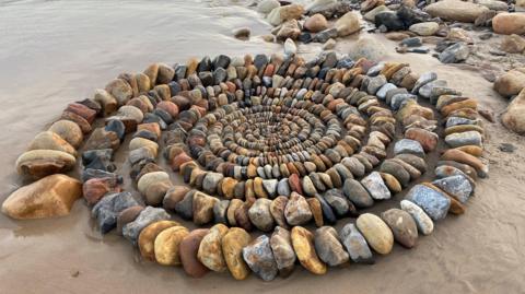 An artwork with hundreds of stones in different colours in a concentric design 