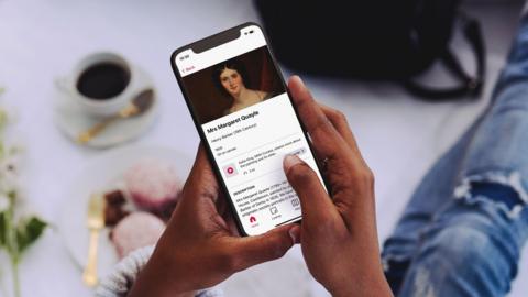 Woman holding phone with Bloomberg Connects app open on the Manx Museum