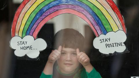 A rainbow drawing is seen as Jake Weller looks through the window of his house as the spread of the coronavirus disease (COVID-19) continues, Aylesbury, Britain