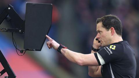 Darren England checks the VAR monitor pitchside