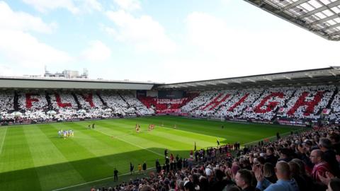 A view of the memorial spread across two stands in white and red reading "Fly High"