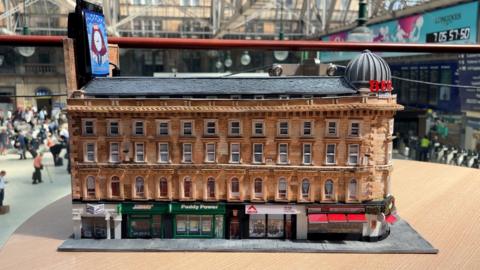 Miniature model of Union Corner in Glasgow, the sandstone building has a dome at the top and a cafe at ground level