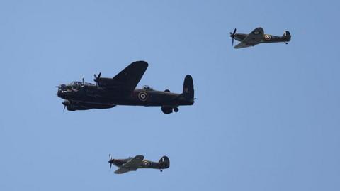 Flypast of the Battle of Britain Memorial Flight's Lancaster bomber and a Hurricane and Spitfire fighters in a clear blue sky