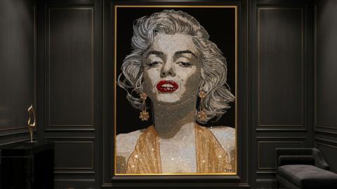 A portrait of Marilyn Monroe made out of crystals. She is wearing a gold top with red lipstick.