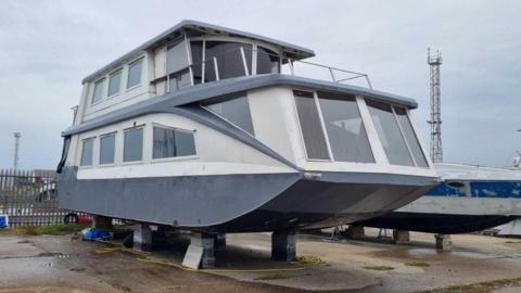 The top section of Derek Abbott's boat Swallow stands on bricks in a boatyard