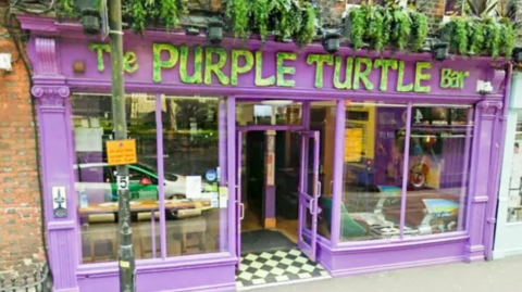 The Purple Turtle Bar and Music venue, a red brick building with a purple frontage and green lettering.