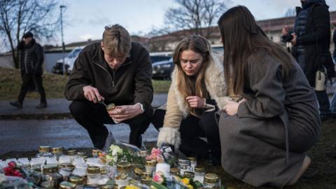 eople light candles at a makeshift vigil near the adult education center Campus Risbergska school in Orebro