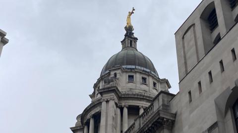 The outside of the Old Bailey court in London. The camera is pointing upwards towards the building.