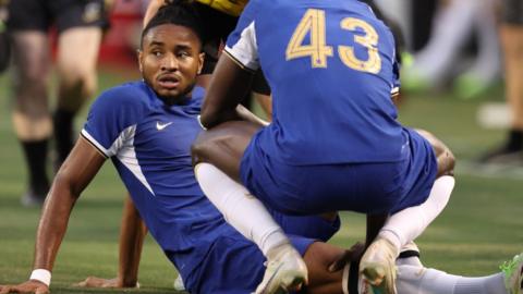 Christopher Nkunku sits on the floor after suffering an injury