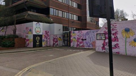 A Google maps image of some highly decorate hoardings surrounding a large, multi-storey bruck council building.