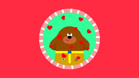 Duggee from Hey Duggee, a brown cartoon dog, in a round badge frame surrounded by hearts.