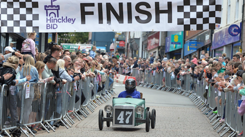 Driver in crash helmet in soap box car 