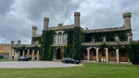 An exterior photo of Lincoln Crown Court, a castle building with arches and columns, covered in dark green ivy.