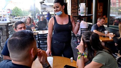 Waitress serves customers while masked