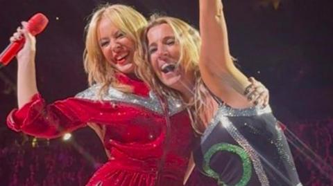 Kylie Minogue on stage with fan Faye Louise smiling at O2 in London.