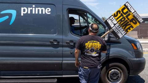 Teamsters union members talks to a truck driver at an Amazon facility in Los Angeles during a labour a strike in 4 August, 2024.