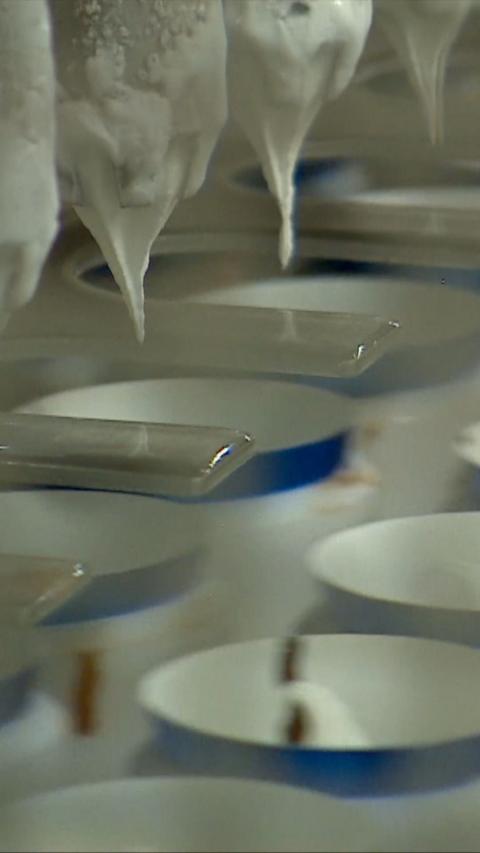 Ice cream being poured into tubs in a factory.