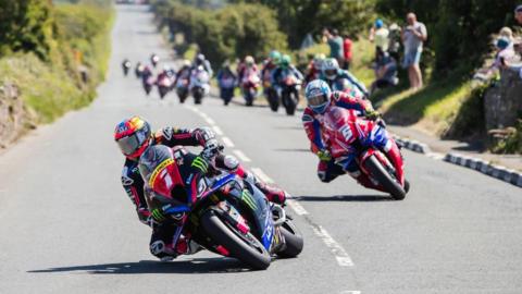 Davey Todd ahead on the road with a string of other bikes following behind.