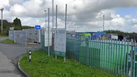 St Austell's Household Waste and Recycling Centre, from the road outside, showing signs and a metal fence