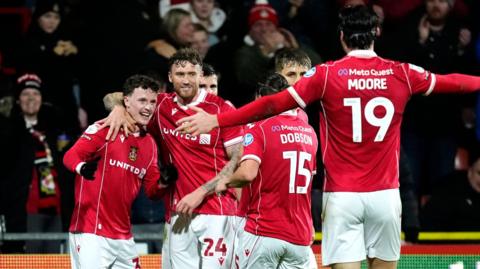 Wrexham forward Nathan Broadhead (L) celebrates with (L to R) Dan Scarr, George Dobson and Kieffer Moore