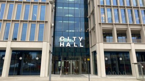 The outside of Sunderland City Hall which is a large building with large rectangle windows with 'City Hall' written in large white letters above the glass entrance.