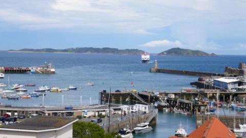 The coast off of Guernsey. There is a large body of water with boats visible.