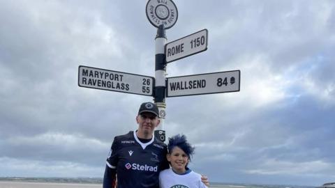 Jacob Alltree, right, and his dad Dale at a sign post at Bowness-on-Solway