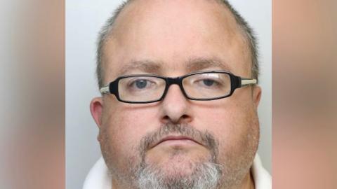 Man with very short light-coloured hair, a short beard and glasses