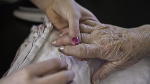 Elderly person's hand being comforted by a younger hand