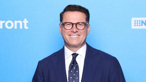 Karl Stefanovic poses in front of a blue wall