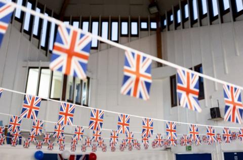 Union Jack bunting adorns the ceiling of a school to mark VE Day