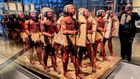 A visitor takes a photo of Pharaonic statues displayed at the Grand Staircase of the Grand Egyptian Museum