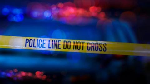 Yellow police tape and police car lights