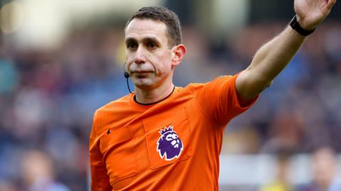Referee at football match with hand in the air