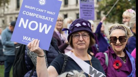 A woman holds a placard  in a protest outside parliament in London in October 2024