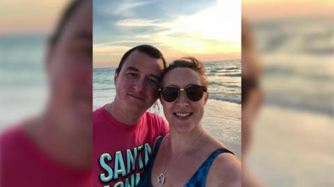 John Walker with his arm around his wife Sue on a sun-kissed beach