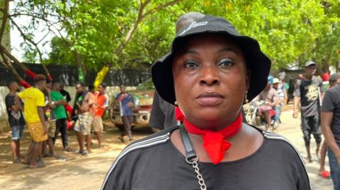 Serwaa Akoto, a protester wearing red and black clothing, speaks to the BBC.