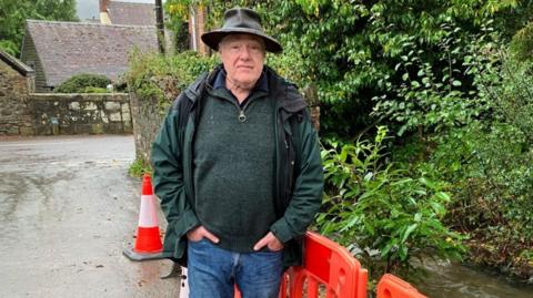 Andy Munro in a hat by the stream that burst its banks