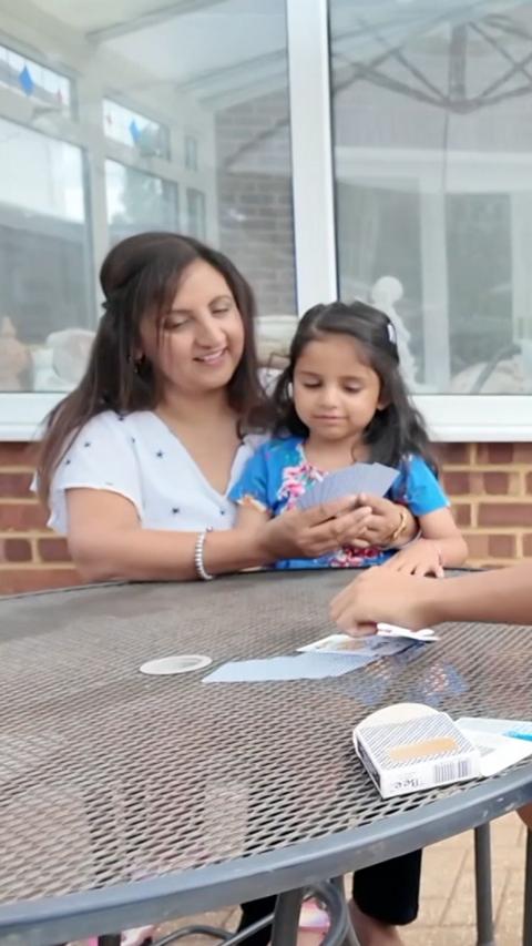 A woman sits with her daughter at a table outside.