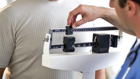 Stock image of a man being weighed in hospital