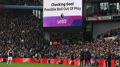 The big screen displays an ongoing VAR (Video Assistant Referee) review for a ball being out of play after Villa score