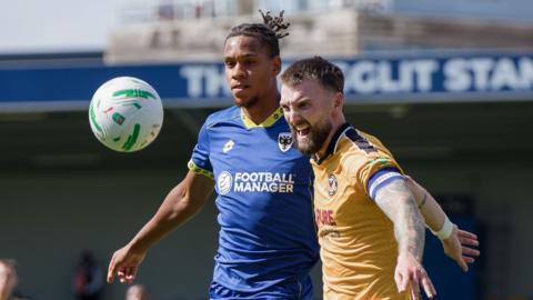 Wimbledon's Alistair Smith and Newport's Kyle Cameron battle for the ball