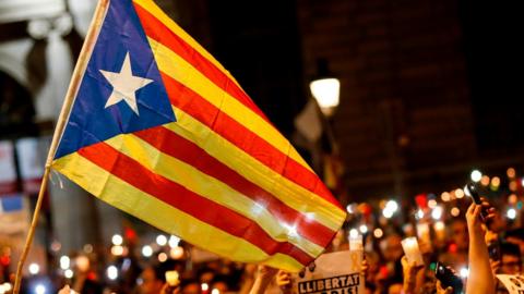 People hold candles and a Catalan pro-independence "Estelada" flag during a demonstration in Barcelona against the arrest of two Catalan separatist leaders