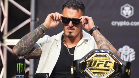 Tom Aspinall puts sunglasses on with the UFC belt in front of him